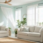 Salon lumineux en été : canapé en lin clair, rideaux légers, ventilateur de plafond en bois et plantes vertes
