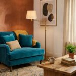 Salon avec mur terracotta et fauteuil bleu canard en velours, lampe laiton