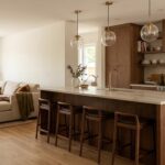 Îlot central en bois avec tabourets délimitant une cuisine ouverte sur un salon