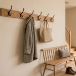 Porte-manteau mural en chêne avec patères noires dans une entrée claire, manteau et cabas suspendus
